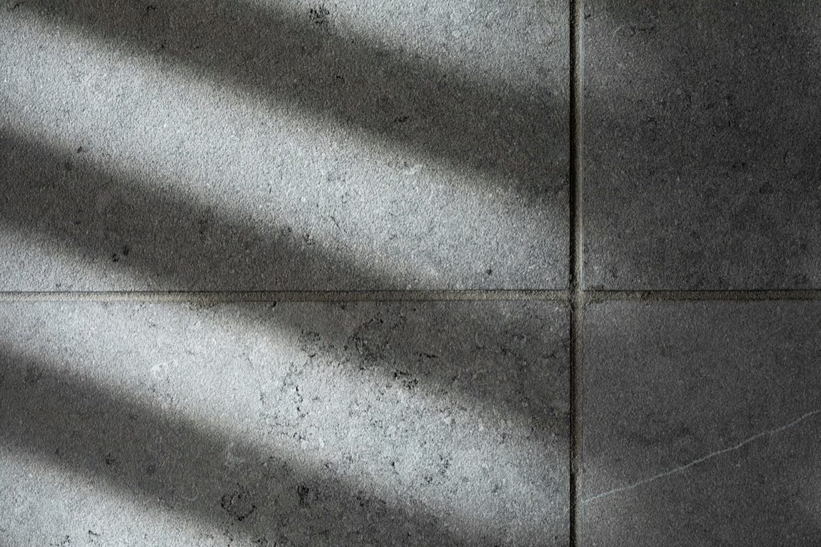 Close-up of dark charcoal concrete-look tiles with a visible joint