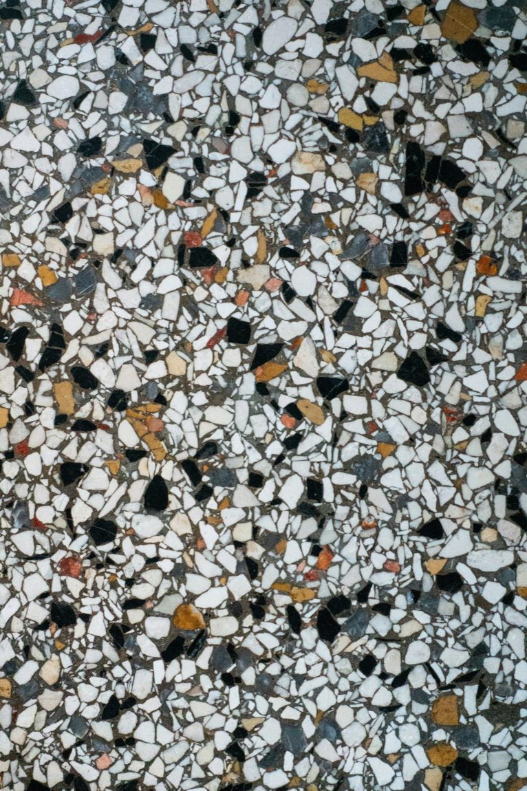 Close-up of pale terrazzo with black, grey and amber stone chips